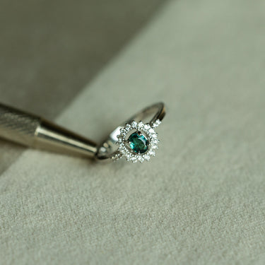 0.40ct natural alexandrite ring in 18k white gold with diamond halo setting on textured surface